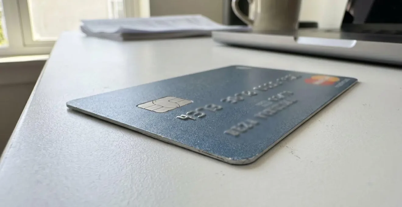 Gros plan sur une carte bancaire moderne posée sur un bureau blanc épuré avec un arrière-plan flouté